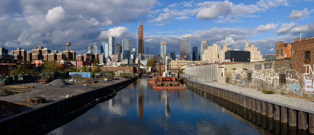 Panorama of the Gowanus Canal from the Union Street Bridge, with a barge, graffiti walls and Downtown Brooklyn towers behind