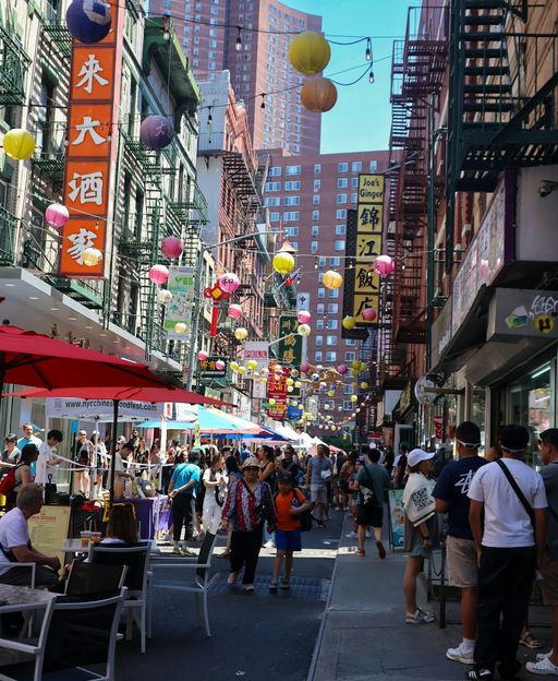 Crowded Mott Street in New York Chinatown beneath hanging lanterns