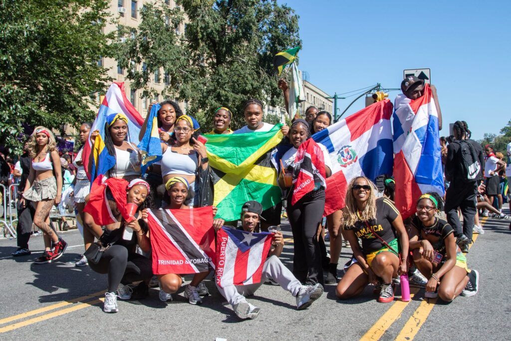 People holding Jamaican, Trinidad and Tobago, Dominican and Puerto Rican flags at a New York City street parade