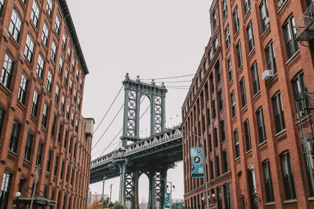 The Manhattan Bridge seen between red brick buildings in Dumbo, Brooklyn