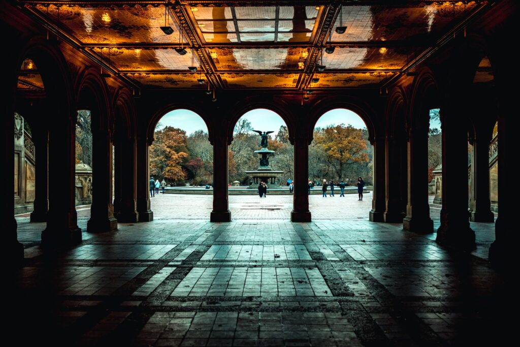 The tiled Arcade beneath Bethesda Terrace, looking out through its arches to the Angel of the Waters fountain in autumn