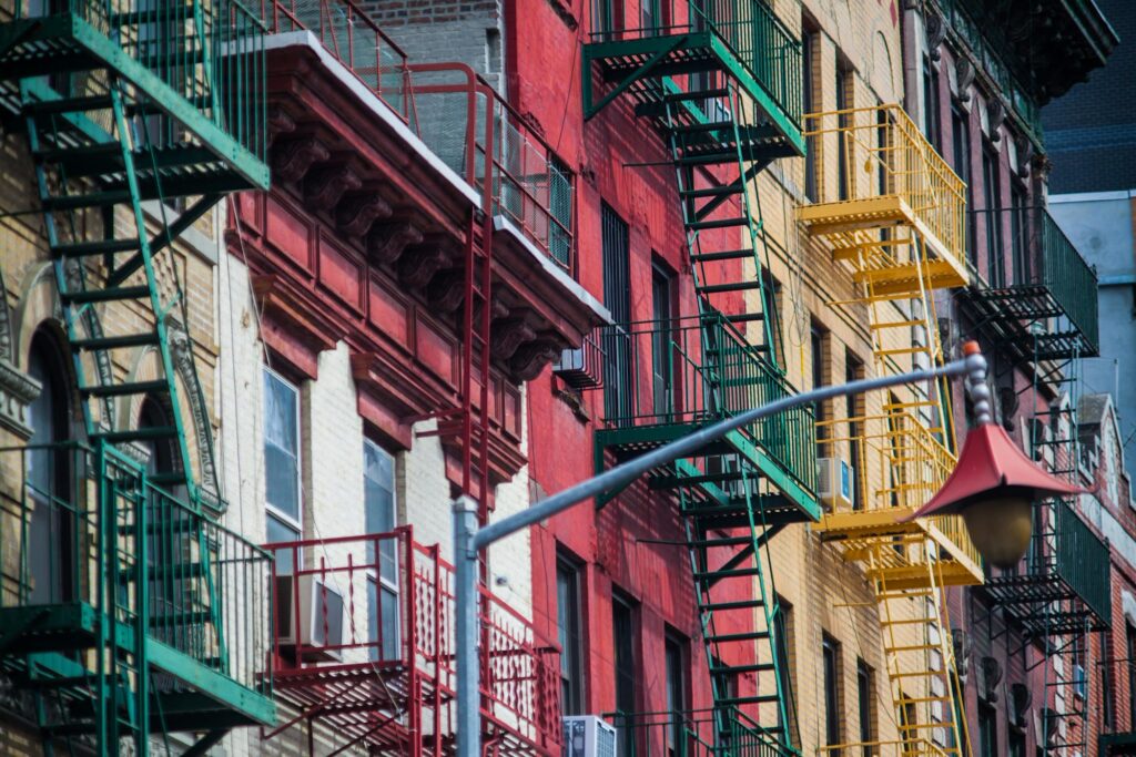 Green, red and yellow fire escapes on old tenement buildings in Little Italy, Manhattan