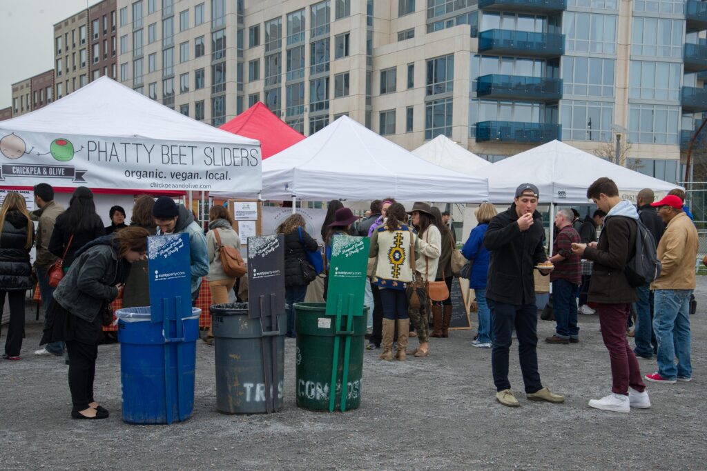 Food stalls under white tents and visitors eating at Smorgasburg in Brooklyn