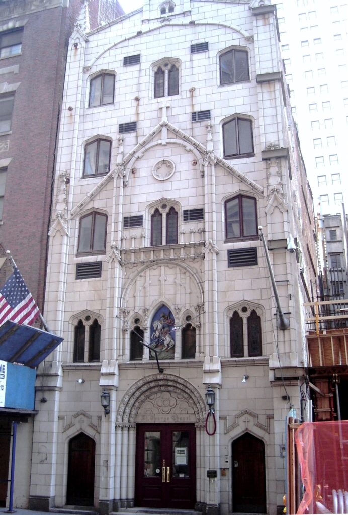 White terra-cotta Gothic facade of the former St. George's Syrian Catholic Church at 103 Washington Street, with a St. George relief above the door