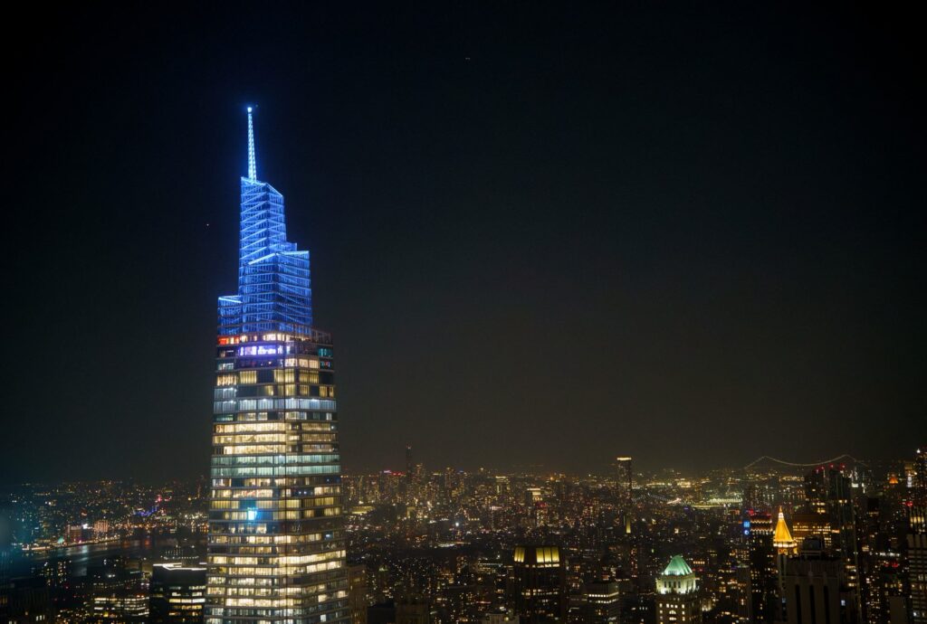 One Vanderbilt tower with its crown lit blue above Midtown at night