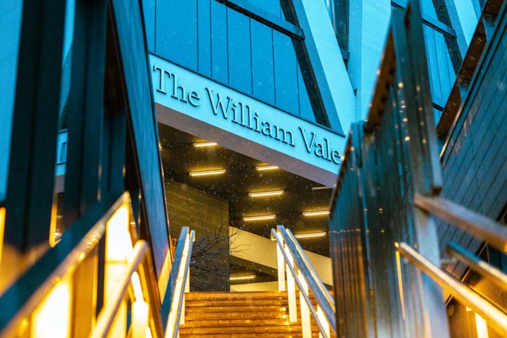 Lit steps leading up to The William Vale hotel sign in Williamsburg at dusk, the building that houses the Westlight rooftop bar