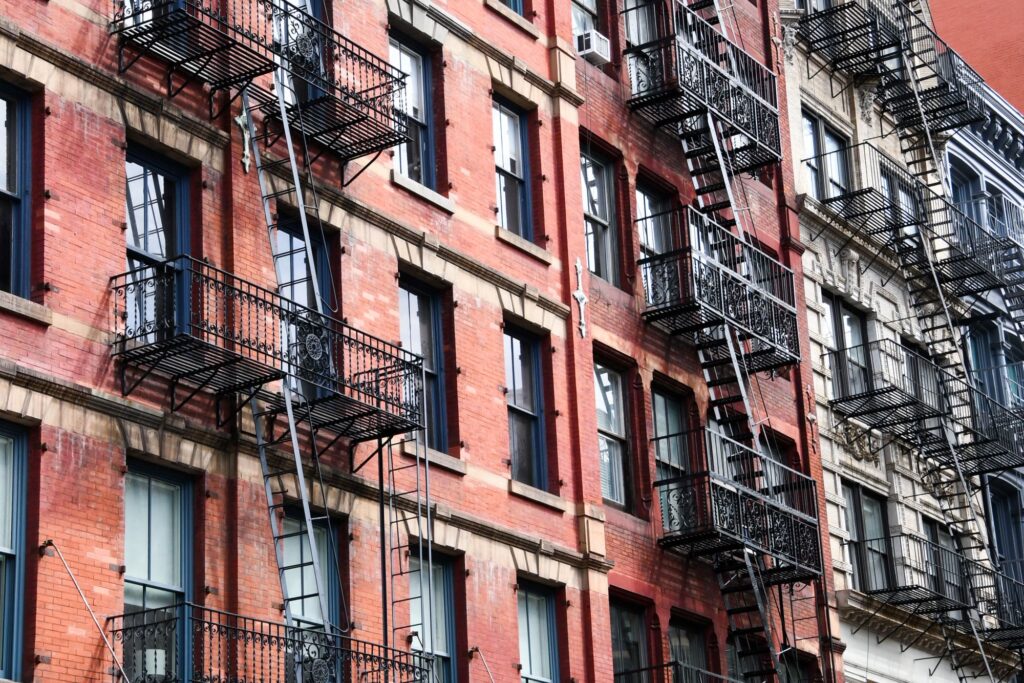Old New York brick tenement facade with iron fire escapes