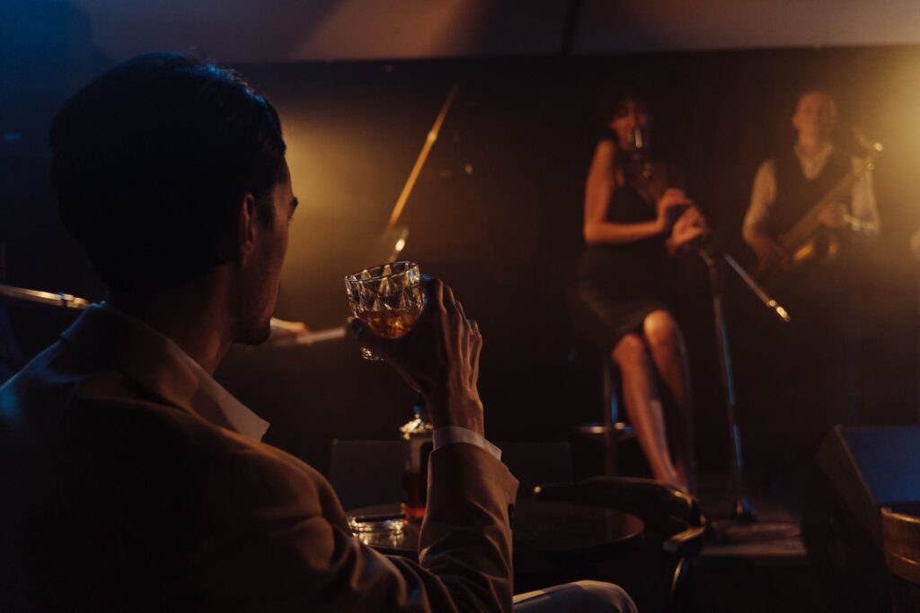 A jazz band on a small club stage, with a guest at a table in the foreground