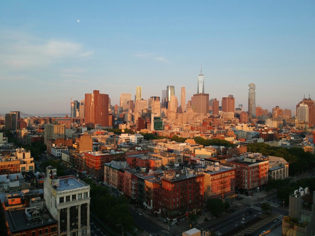 Red-brick Lower East Side blocks at sunrise with the Lower Manhattan skyline behind